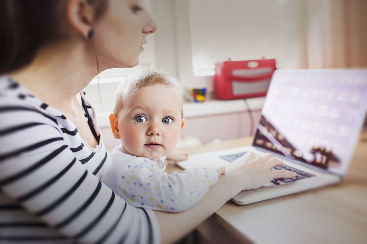 Mother shopping on laptop computer with baby on lap